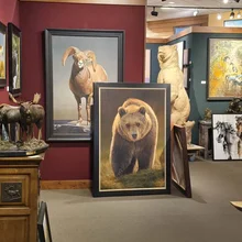 realistic paintings and sculptures of a bear, a ram, and moose displayed in a gallery with neutral and warm-colored walls